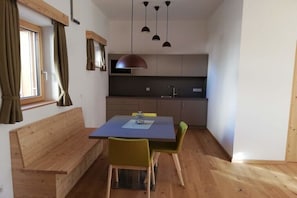 A compact kitchen with a dining area, wooden bench, and pendant lighting. - At Niedermoar- "Brenngass" (Naturns)