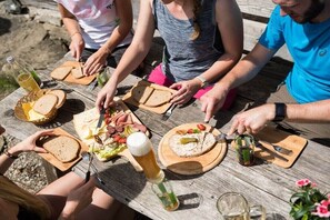 A group of people dining at an outdoor wooden table with various food items and drinks. - Holiday apartment with 1 bedroom (Bolsterlang)