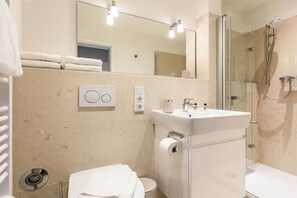 Ein modernes Badezimmer mit einer Duschkabine, einem weißen Waschbecken und einer Toilette.