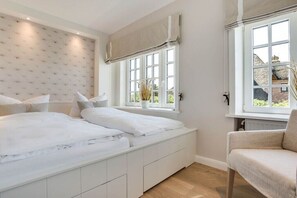 Ein Schlafzimmer mit Bett, Fenster, Stuhl und Heizkörper.