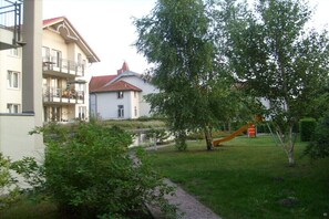 A residential area with a white building, a tree, and a yellow slide. - Holiday apartment with 2 bedrooms (Graal-Müritz)