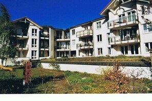 Ein mehrstöckiges Wohngebäude mit Balkonen, einem Weg und einer kleinen Grünfläche.