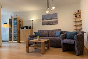 Ein Wohnzimmer mit einer Couch, einem Couchtisch, einem Bücherregal und einem Bild an der Wand.