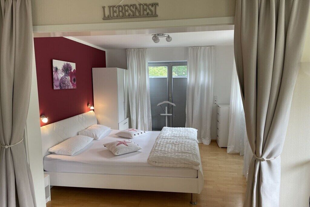 A bedroom with a bed, a wardrobe, a window with curtains, and a wall-mounted sign.