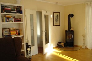 A living room with a fireplace, a bookshelf, and a door leading to another room. - "Witt Hus" Home office and vacation (St-Peter Ording (Böhl))