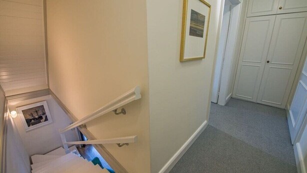 A staircase with white handrails, a small framed picture on the wall, and a closet with white doors. - Holiday home in Kampen with swimming pool (Kampen)