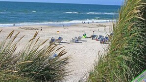 Ein Strand mit Menschen, Liegestühlen und Sonnenschirmen.