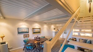 A dining area with a wooden table and chairs, a staircase with white railings, and a view of the upper floor. - Holiday home in Kampen with swimming pool (Kampen)