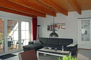A living room with a dark sofa, a white coffee table, and a glass cabinet with decorative items. - Holiday home with 2 bedrooms (Wangerland-Hooksiel)