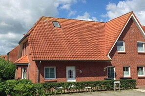 A red-brick building with a tiled roof, a small window, and a door. - Holiday home with 2 bedrooms (Wangerland-Hooksiel)