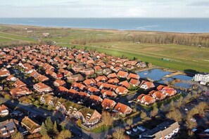 An aerial view of a residential area with houses, a golf course, and a body of water. - Holiday home with 2 bedrooms (Wangerland-Hooksiel)