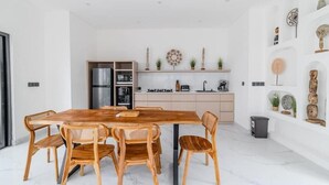 Een moderne keuken met een houten eettafel en stoelen, een inbouwoven en een witte inrichting.