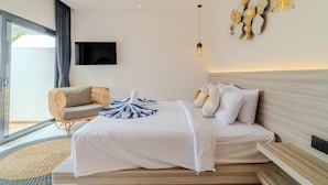 Een moderne hotelkamer met een groot bed, een zithoek met een stoel, een flatscreen televisie en uitzicht op het omliggende landschap.