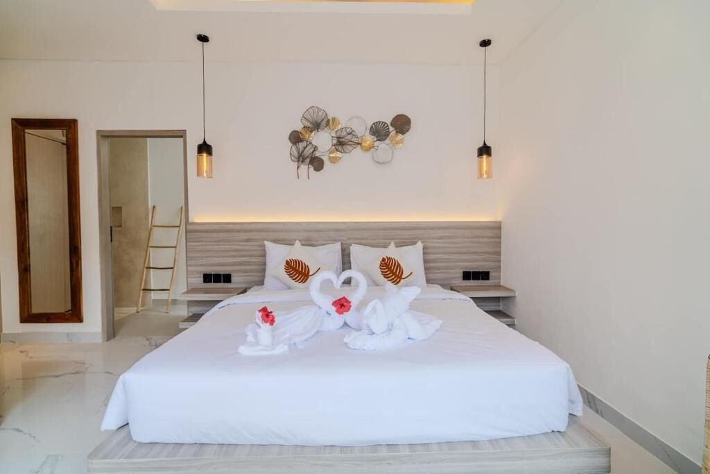 Een hotelkamer met een groot bed, twee nachtkastjes, een spiegel en een kunstwerk aan de muur.
