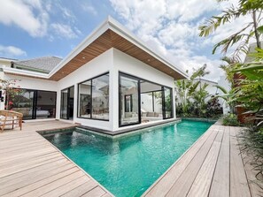 Uma casa moderna com piscina, amplas janelas de vidro e um deck de madeira.