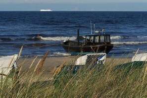 Een boot op een zandstrand met de oceaan op de achtergrond.
