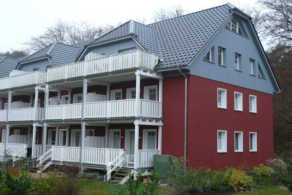 Een gebouw met twee verdiepingen, een balkon op de bovenverdieping, een rode gevel en een grijs dak.