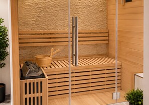 A sauna with wooden benches, a metal sauna heater, and a stone wall backdrop. - Appartement Eifelglück (Pelm)
