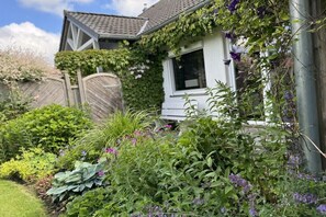 A house with a garden in front, a wooden fence, and a window. - Holiday home in Neufeld with swimming pool (Neufeld)
