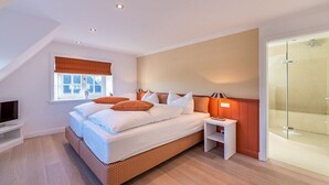 Una camera da letto moderna con un letto grande, un comodino, una TV e un box doccia in vetro.