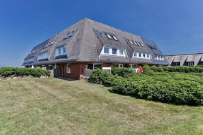 A two-story house with a sloped roof, a front porch, and a well-maintained lawn. - House section Heideblick (Kampen)