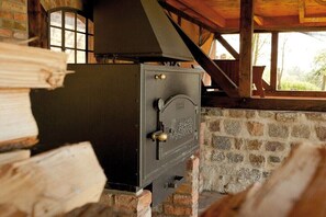A wood-burning stove in a rustic setting with stone walls and wooden beams. - Holiday apartment with 1 bedroom (Usedom)