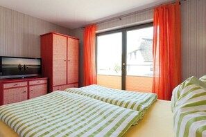Een hotelkamer met een bed, een televisie, een kledingkast en een schuifglasdeur naar buiten.