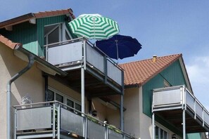 A multi-story building with balconies, a green awning, and a blue umbrella. - Holiday apartment with 1 bedroom (Seebad Ahlbeck)