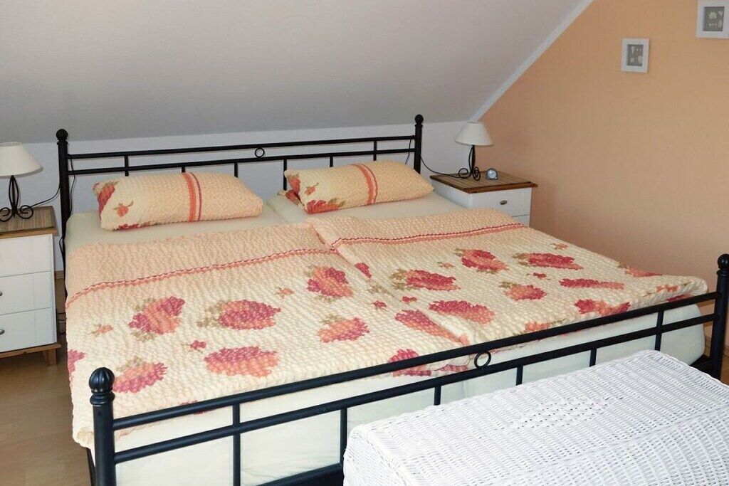 Ein Einzelbett mit einer blumigen Tagesdecke und zwei Nachttische mit Lampen.