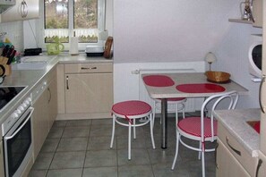 Une cuisine compacte équipée d’une cuisinière, d’un évier et d’un petit coin repas avec deux tabourets.
