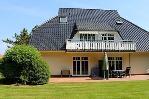Een huis met twee verdiepingen, een balkon, een overdekte patio en een gazon.