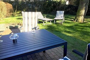 Een terras met een tafel en twee gestreepte loungestoelen.