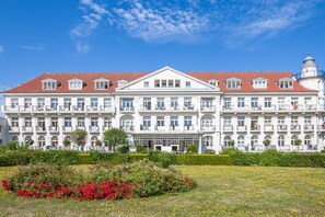 Un hotel grande de varios pisos con fachada simétrica, múltiples balcones y una entrada destacada.