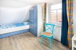 Un dormitorio con cama, armario, silla y ventana.