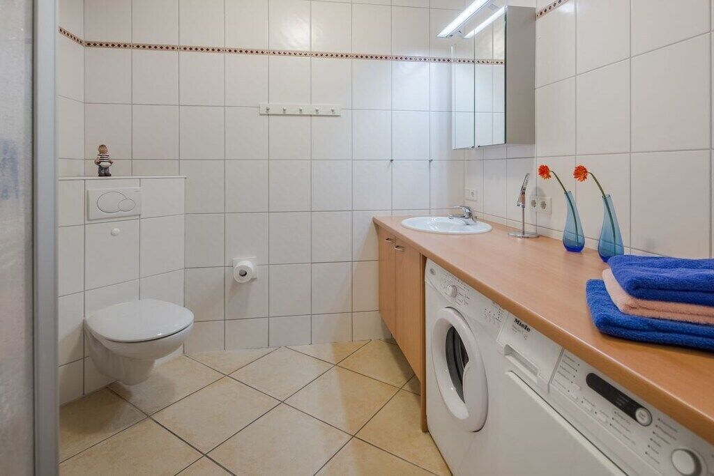 Ein Badezimmer mit Toilette, Waschmaschine, Waschbecken und Spiegel.