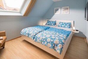 Ein Schlafzimmer mit einem Bett, einem Sessel, einem Nachttisch und einem Fenster.