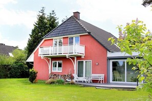 Een tweelaags huis met een balkon, een overdekte patio en een gazon.