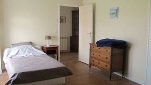 Una camera da letto con un letto, una cassettiera, un comodino e una porta che dà su un'altra stanza.