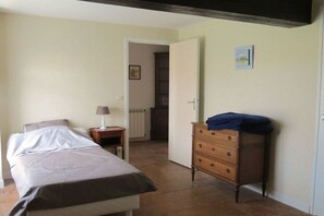 Een slaapkamer met een bed, een kaptafel, een nachtkastje en een deur naar een andere kamer.