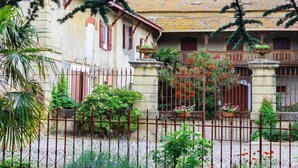 Un edificio tradizionale con un cortile interno, un ingresso chiuso da cancello e un balcone con piante in vaso.