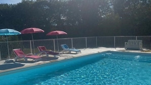 Una piscina con acqua cristallina, circondata da una recinzione in metallo, dotata di numerosi lettini e ombrelloni.
