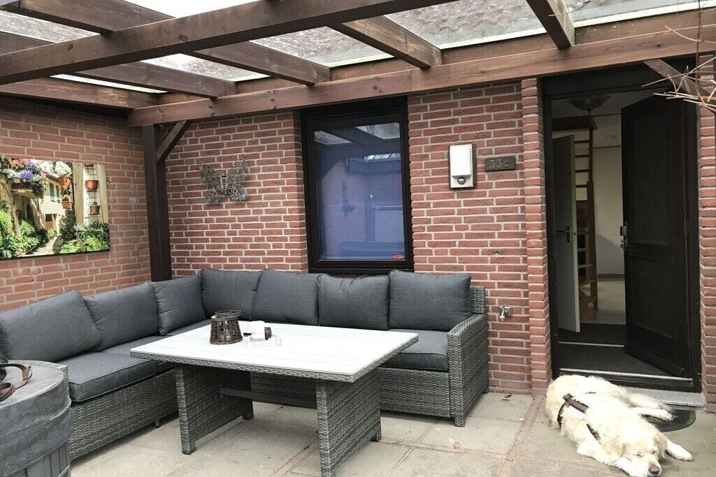 A covered patio with a wicker sofa, a table, and a dog.