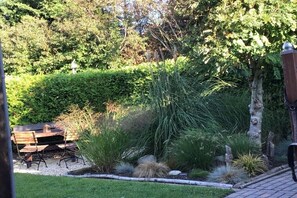 A garden with a wooden bench, a variety of plants, and a stone pathway. - Holiday home with 3 bedrooms (BX Herkingen)