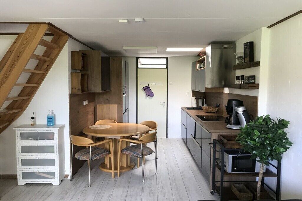 Una cucina compatta con zona pranzo, mobili in legno, una scala e una piccola pianta in vaso.