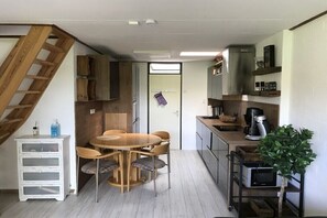 A compact kitchen with a dining area, wooden cabinets, a staircase, and a small potted plant. - Holiday home with 3 bedrooms (BX Herkingen)