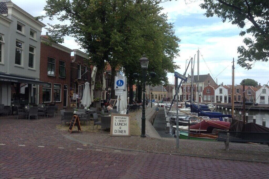 A waterfront restaurant with outdoor seating, a canal, and boats.
