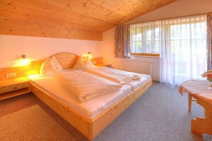 Une pièce confortable avec un lit en bois, des lampes de chevet, une fenêtre avec des rideaux et une petite table.
