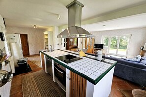 A compact kitchen with a central island, built-in oven, and a stainless steel range hood. - Holiday home with 2 bedrooms (Sierksdorf)