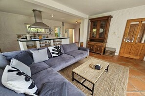 A living room with a grey sofa, a wooden coffee table, and a kitchen in the background. - Holiday home with 2 bedrooms (Sierksdorf)