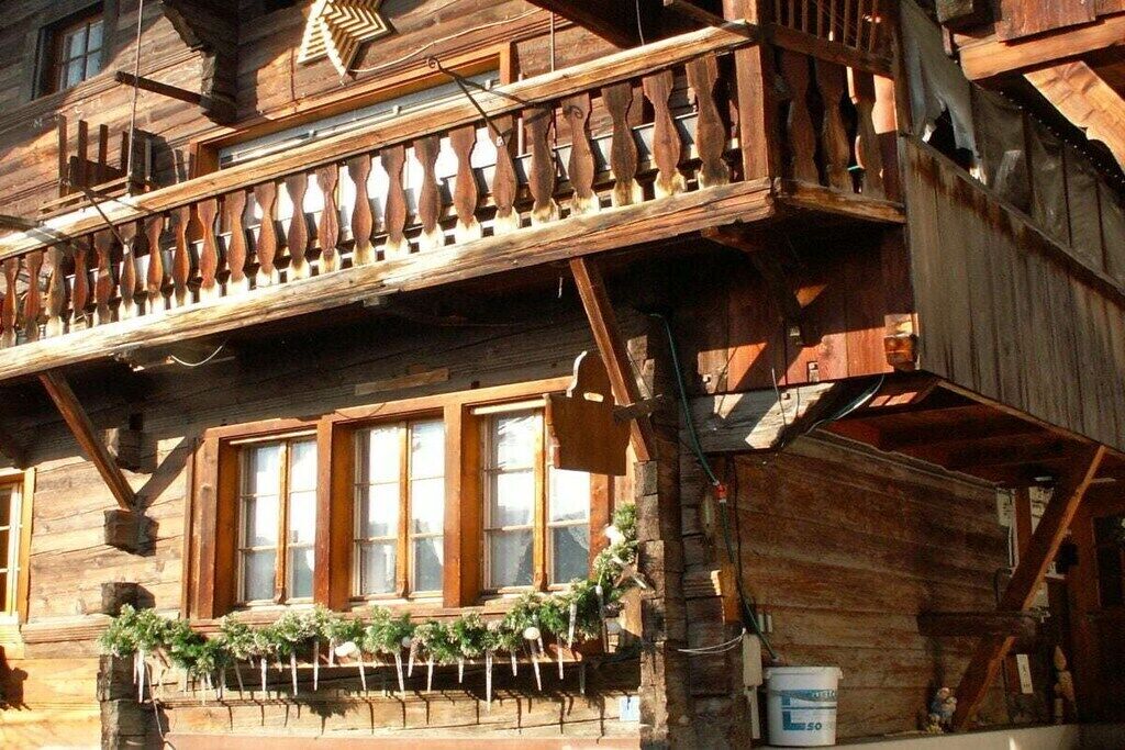 Ein Holzhaus mit Balkon, großen Fenstern und einem Steinfundament.